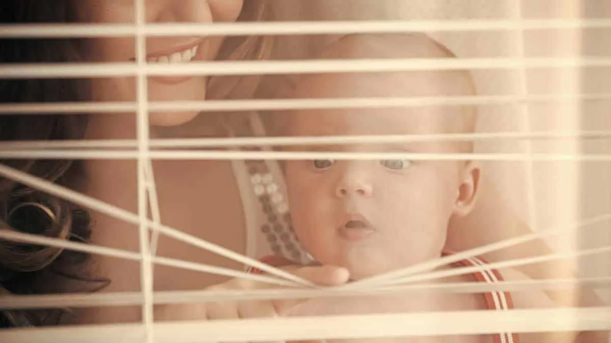 baby with mother looking thru blinds