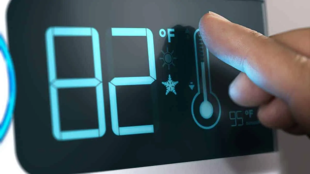 person touching smart thermostat