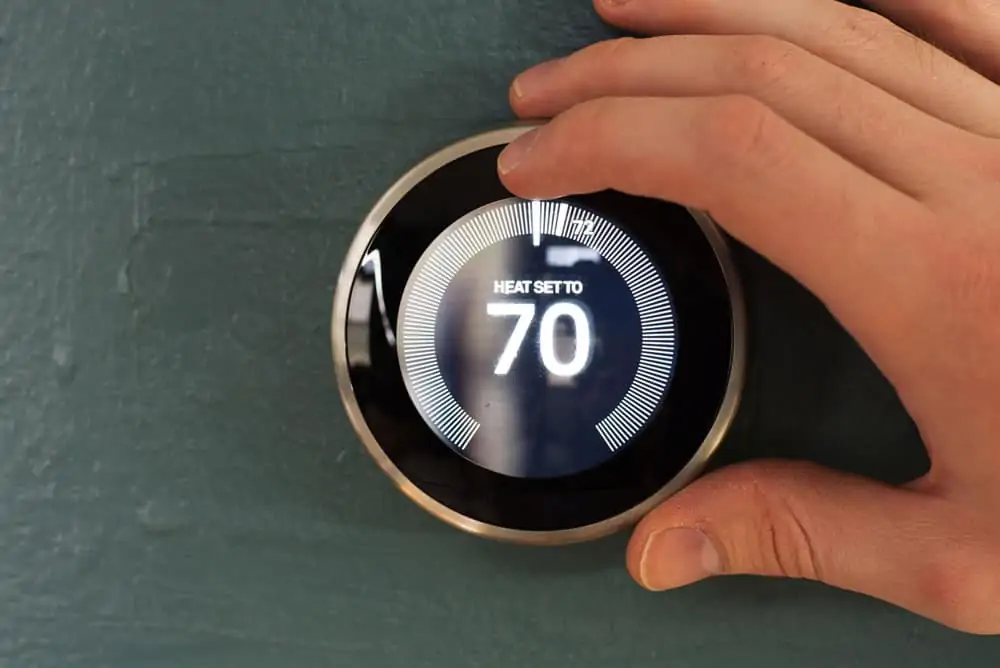 person adjusting Nest smart home thermostat