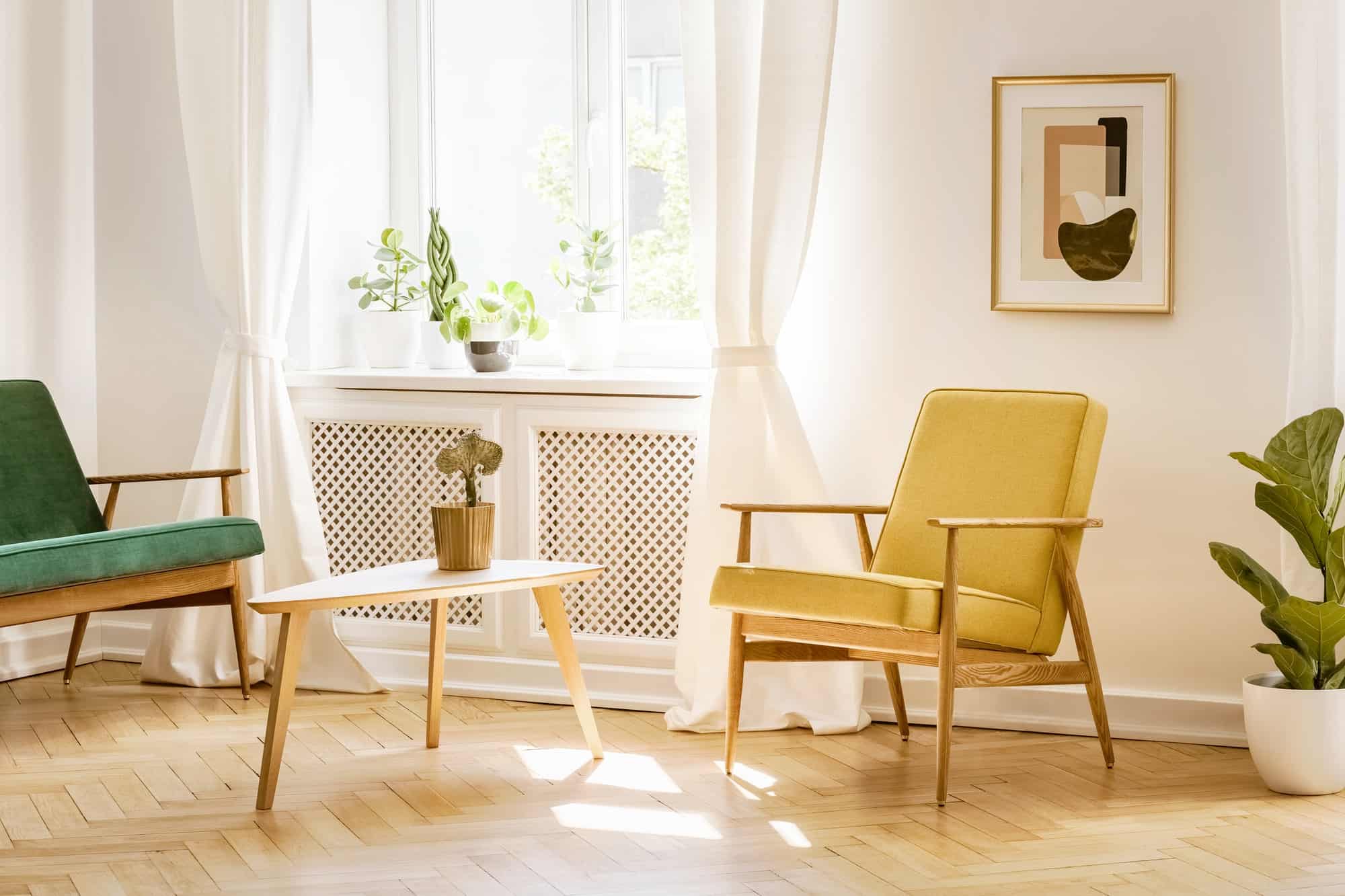 Yellow, retro armchair and a green sofa by a big, sunny window i