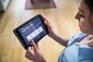 A woman holding a tablet with smart home screen.